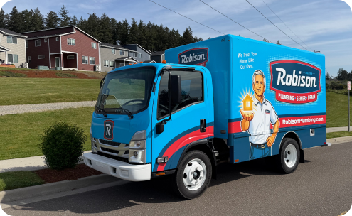 A blue Robison Plumbing service truck is parked on a suburban street near houses, with company branding and a technician illustration on the side.